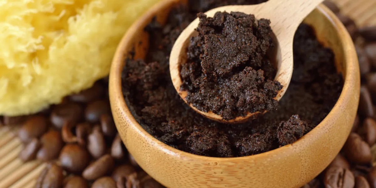 homemade coffee scrub face mask in wooden bowl with spoon on coffee beans