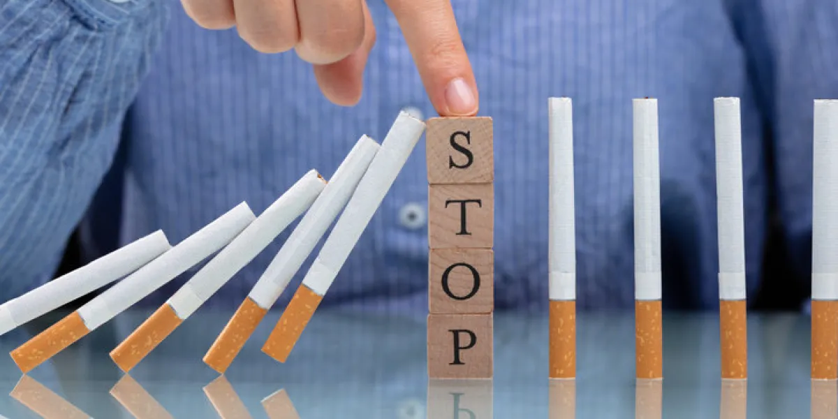 woman stopping cigarette from falling on desk with wooden blocks woman stopping cigarette from falling on desk with wooden blocks