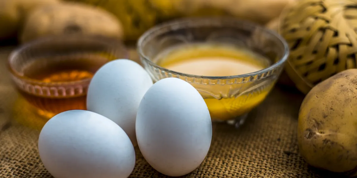 potato juice plus honey plus egg yolk face mask for dry and damaged hair on the wooden surface along with raw potato, egg and honey present on the surface potato juice plus honey plus egg yolk face mask for dry and damaged hair on the wooden surface along with raw potato, egg and honey present on the surface