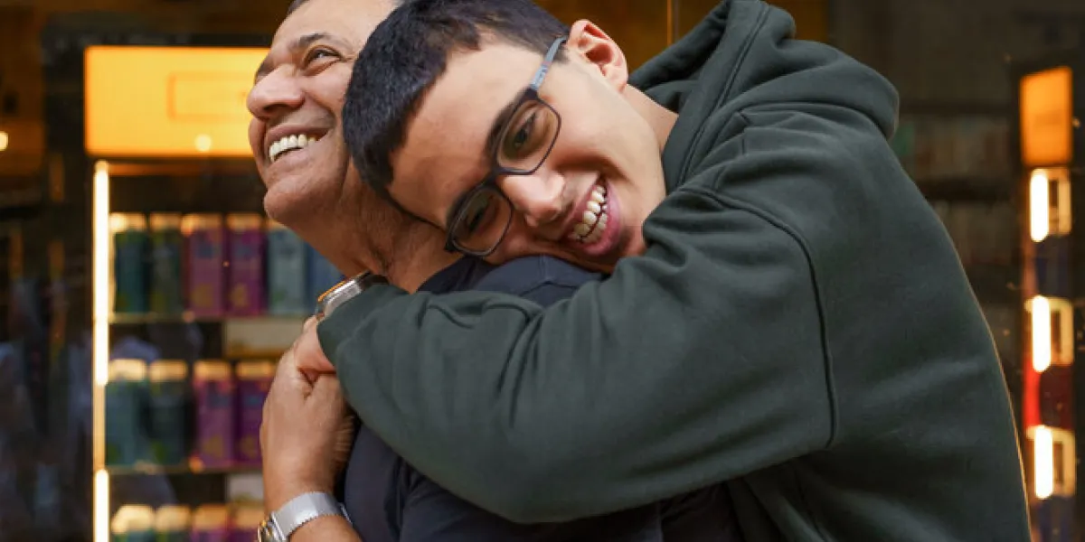 hug for dad a teen boy leans over to hug his father, who to be smiling at him