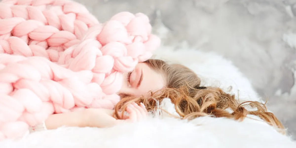 young woman with long brown hair sleeping under warm knitted peach color throw blanket young woman with long brown hair sleeping under warm knitted peach color throw blanket