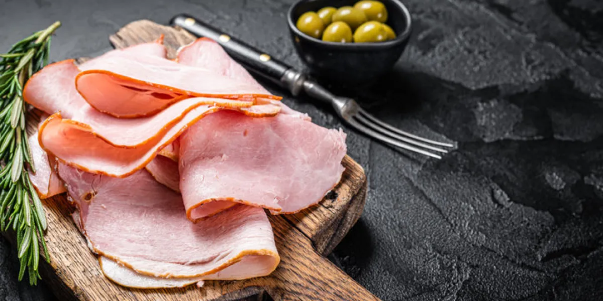 pork ham slices on cutting board, italian prosciutto cotto black background top view copy space