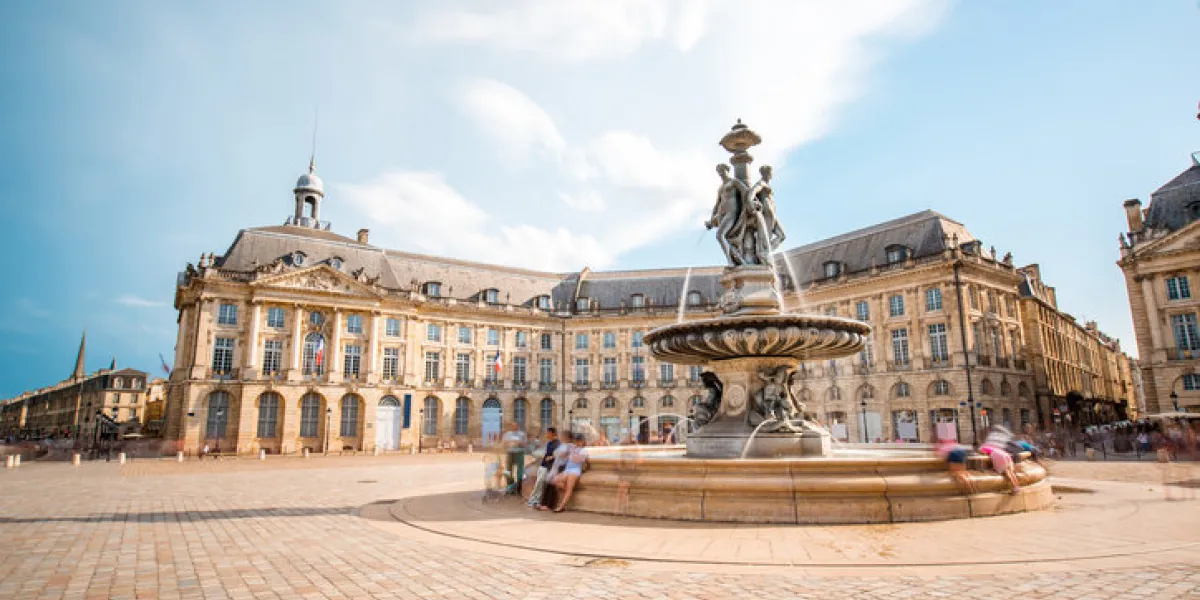 view on the famous la bourse square with fountain in bordeaux city, france long exposure image technic with motion blurred people and clouds view on the famous la bourse square with fountain in bordeaux city, france long exposure image technic with motion blurred people and clouds