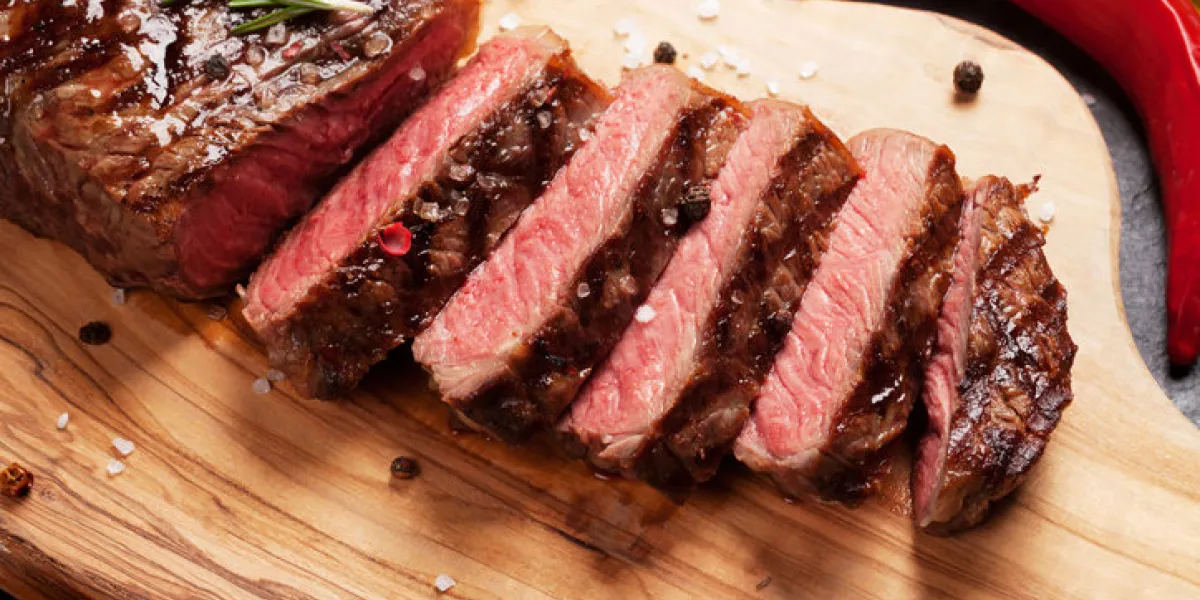 grilled striploin sliced steak on cutting board over stone table grilled striploin sliced steak on cutting board over stone table