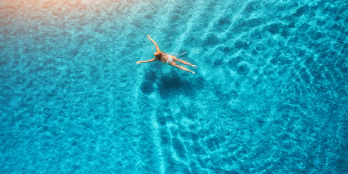 aerial view of swimming woman at sunset in maldives mediterranean sea aerial seascape with young girl, clear blue water, waves in summer transparent water top view resort on seashore holiday aerial view of swimming woman at sunset in maldives mediterranean sea aerial seascape with young girl, clear blue water, waves in summer transparent water top view resort on seashore holiday