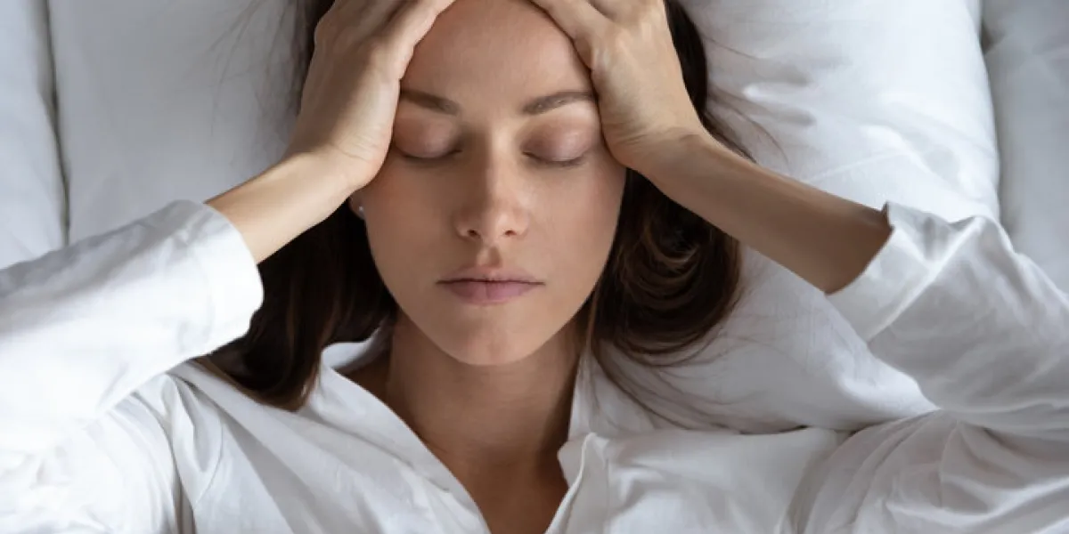 top view close up depressed woman suffering from headache or migraine, touching forehead with hands, lying in bed with closed eyes, unhappy young female feeling bad, pain in head, hangover top view close up depressed woman suffering from headache or migraine, touching forehead with hands, lying in bed with closed eyes, unhappy young female feeling bad, pain in head, hangover