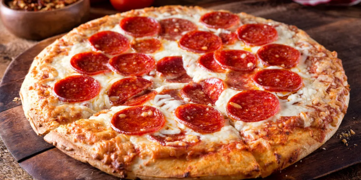 a delicious brick oven baked pepperoni pizza on a rustic wood serving board