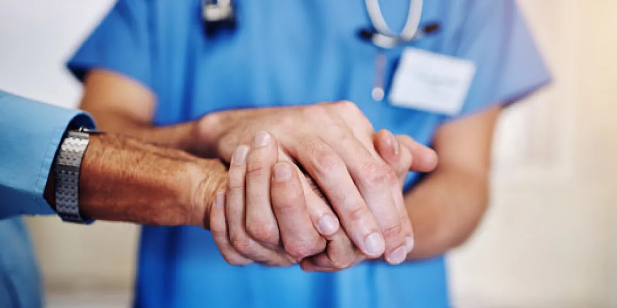 shot of an unidentifiable young doctor holding his senior patient's hand in support