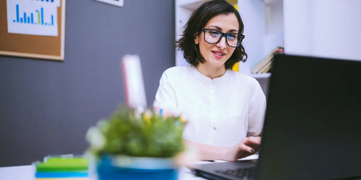 brunette woman in eyeglasses typing morning report at her desk at the office brunette woman in eyeglasses typing morning report at her desk at the office