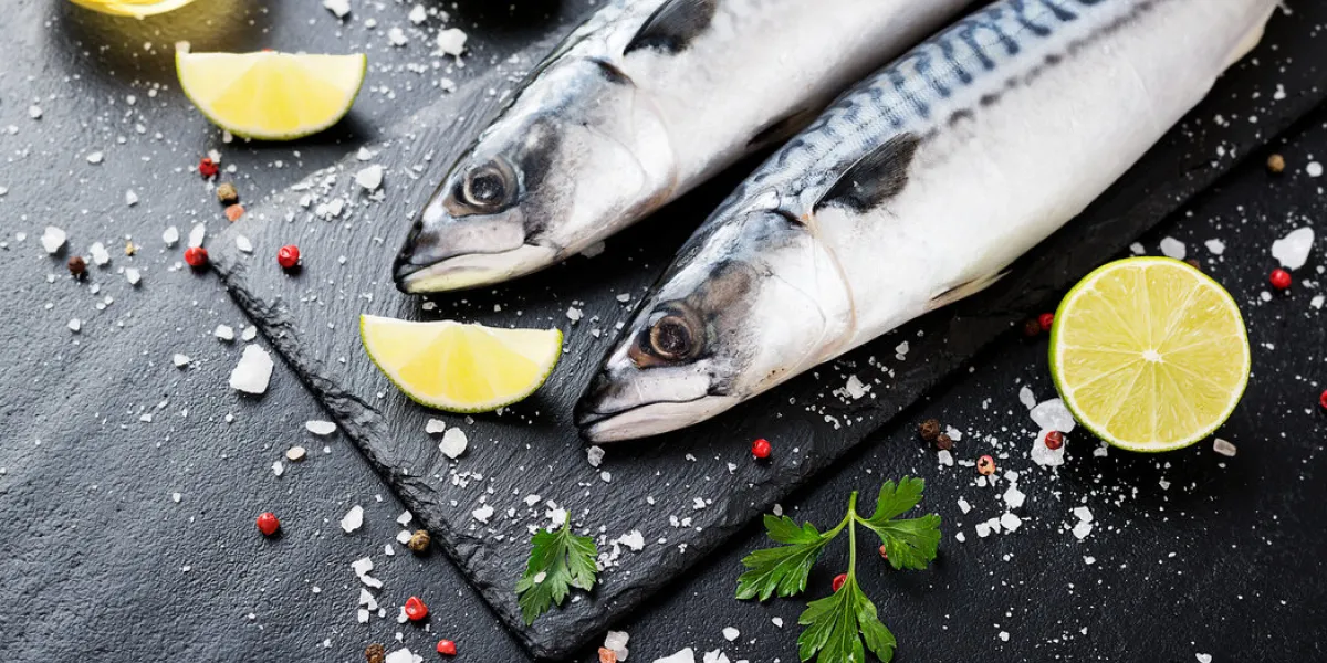 fresh fish mackerel with salt, lemon and spices on black stone