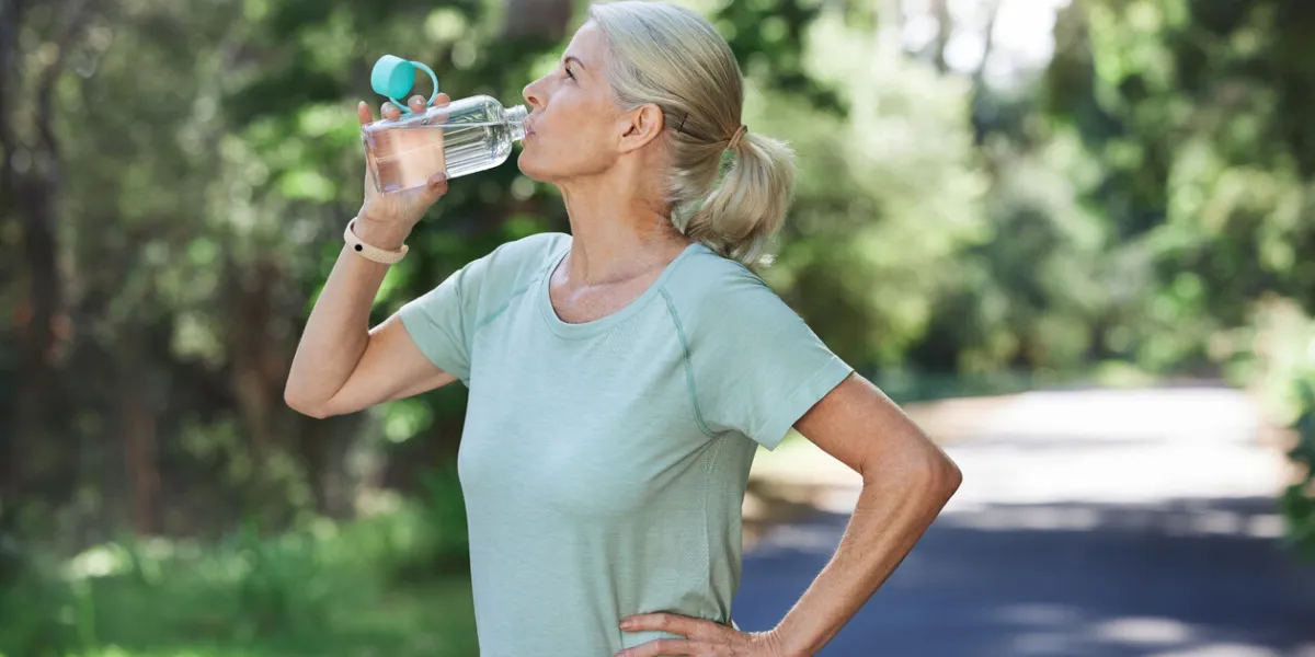 shot of a mature woman drinking water while exercising outdoors