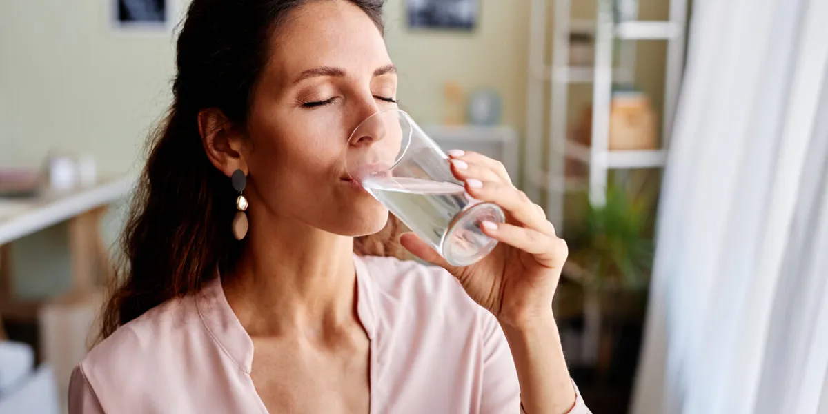 portrait of beautiful adult woman drinking water in morning while starting day at home