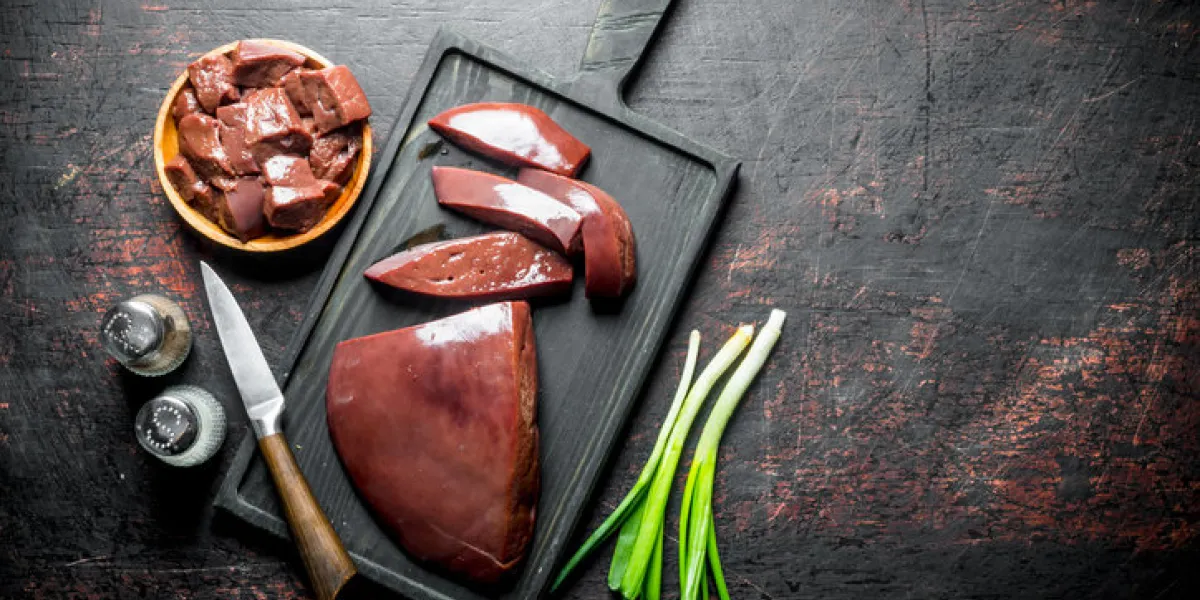 pieces of raw liver in a plate and on a cutting board on dark rustic background pieces of raw liver in a plate and on a cutting board on dark rustic background