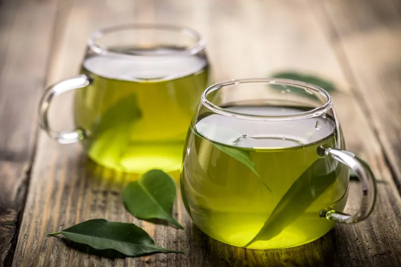 fresh green tea with tea leaves in the water fresh green tea with tea leaves in the water
