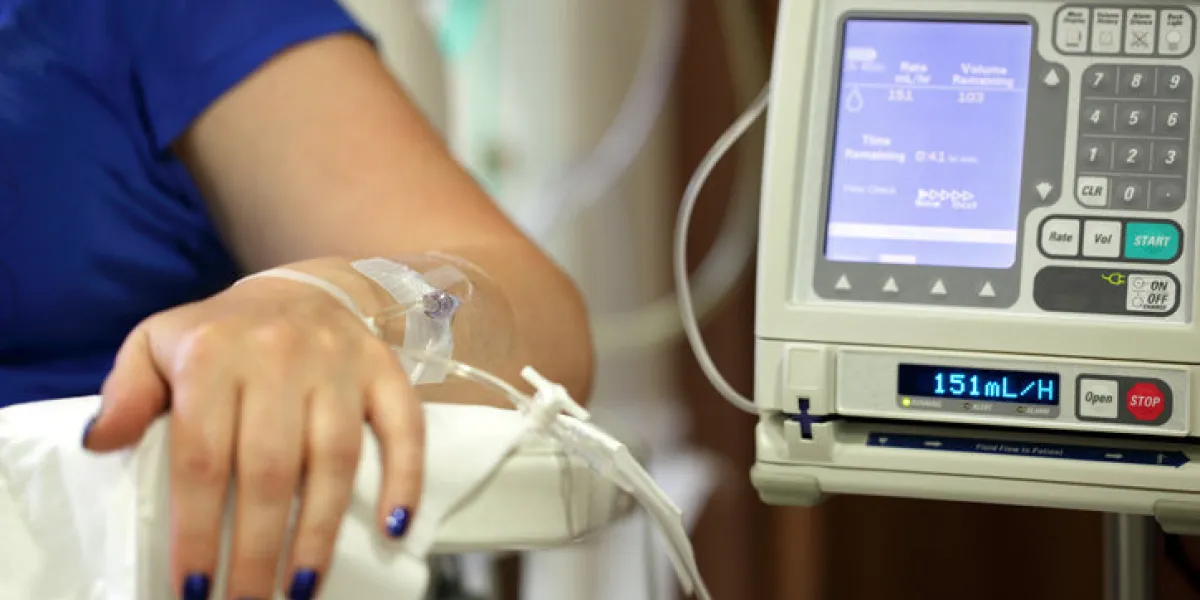 infusion pump feeding iv drip into patients arm focus on needle infusion pump feeding iv drip into patients arm focus on needle