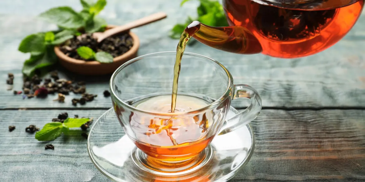 pouring black tea into glass cup on wooden table pouring black tea into glass cup on wooden table