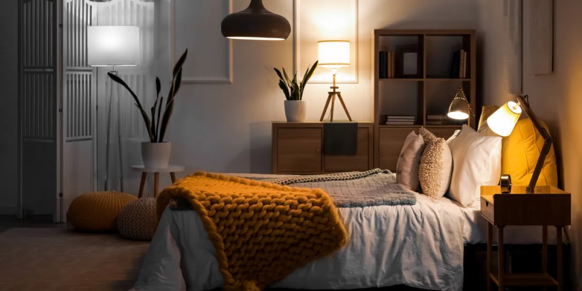 interior of bedroom with knitted plaid on bed and glowing lamps at night interior of bedroom with knitted plaid on bed and glowing lamps at night