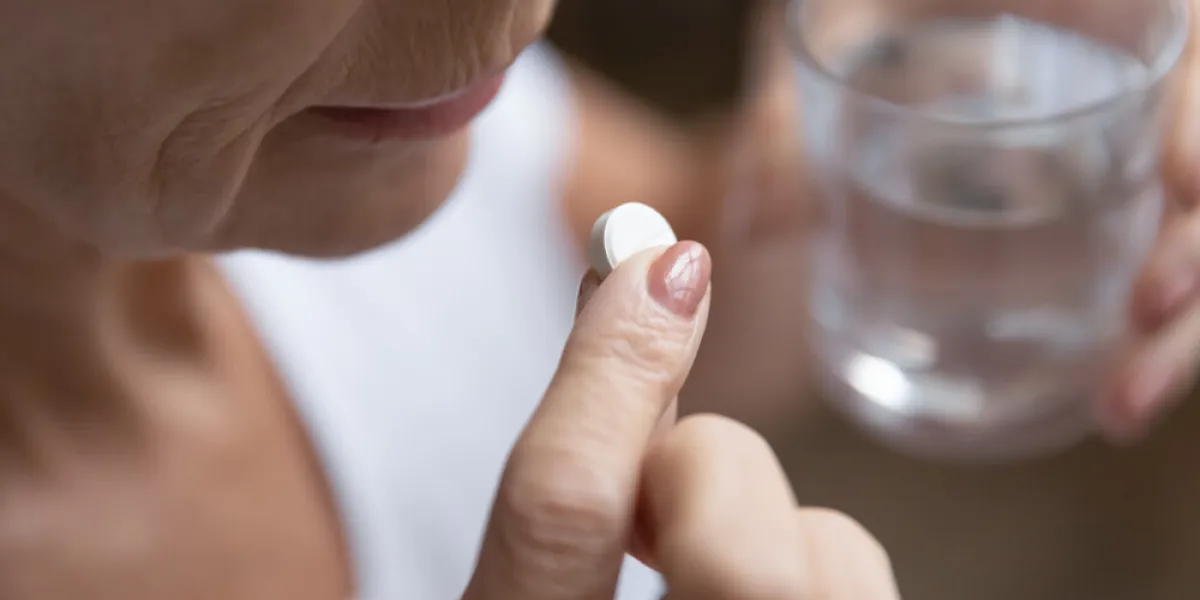 close up senior mature woman taking painkiller, antibiotic, supplements or vitamin medication, middle aged female holding glass of water and white round pill in hands, disease treatment concept close up senior mature woman taking painkiller, antibiotic, supplements or vitamin medication, middle aged female holding glass of water and white round pill in hands, disease treatment concept