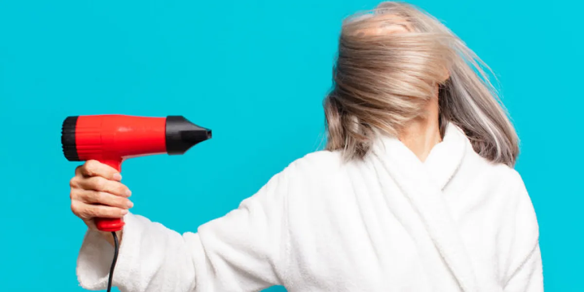 senior pretty woman after shower wearing bathrobe hairdryer concept