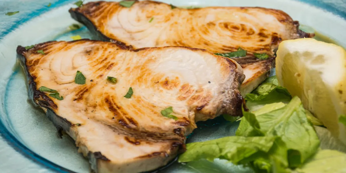 un plat d'espadon pics, parmi les citrons coupés, sur un plat en verre, sur un lit de laitue, prêt à manger, dans une table étalée un plat d'espadon pics, parmi les citrons coupés, sur un plat en verre, sur un lit de laitue, prêt à manger, dans une table étalée