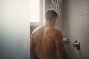 plan moyen d'un homme musclé vu de dos en train de prendre sa douche