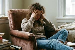 une jeune femme dans un fauteuil. Elle est fatiguée et se tient la tête
