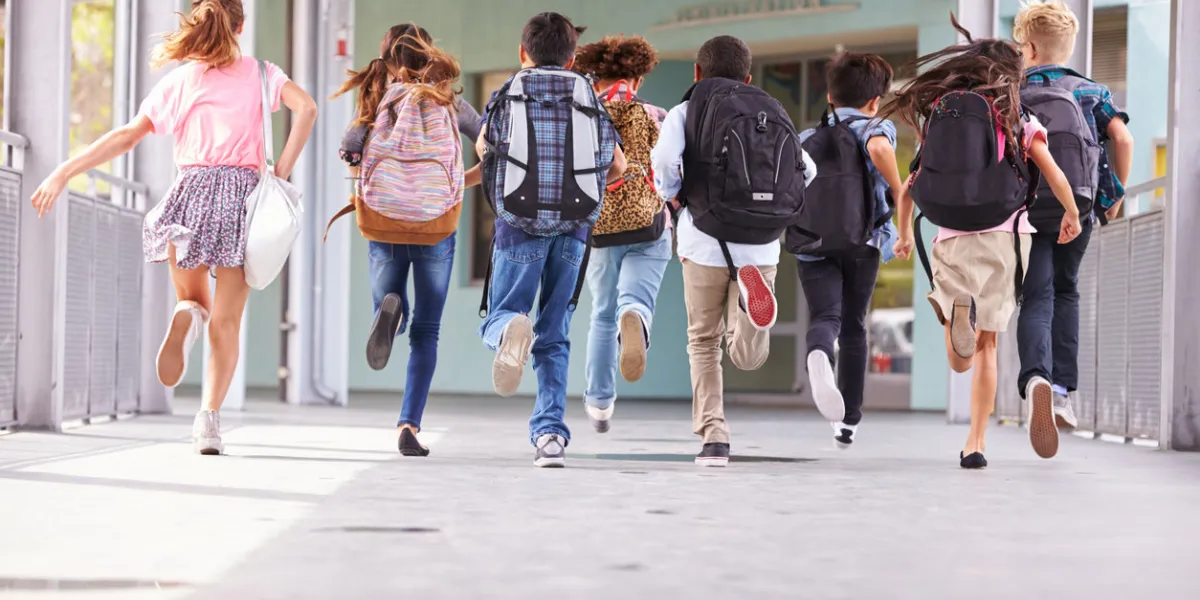 group of elementary school kids running at school, back view