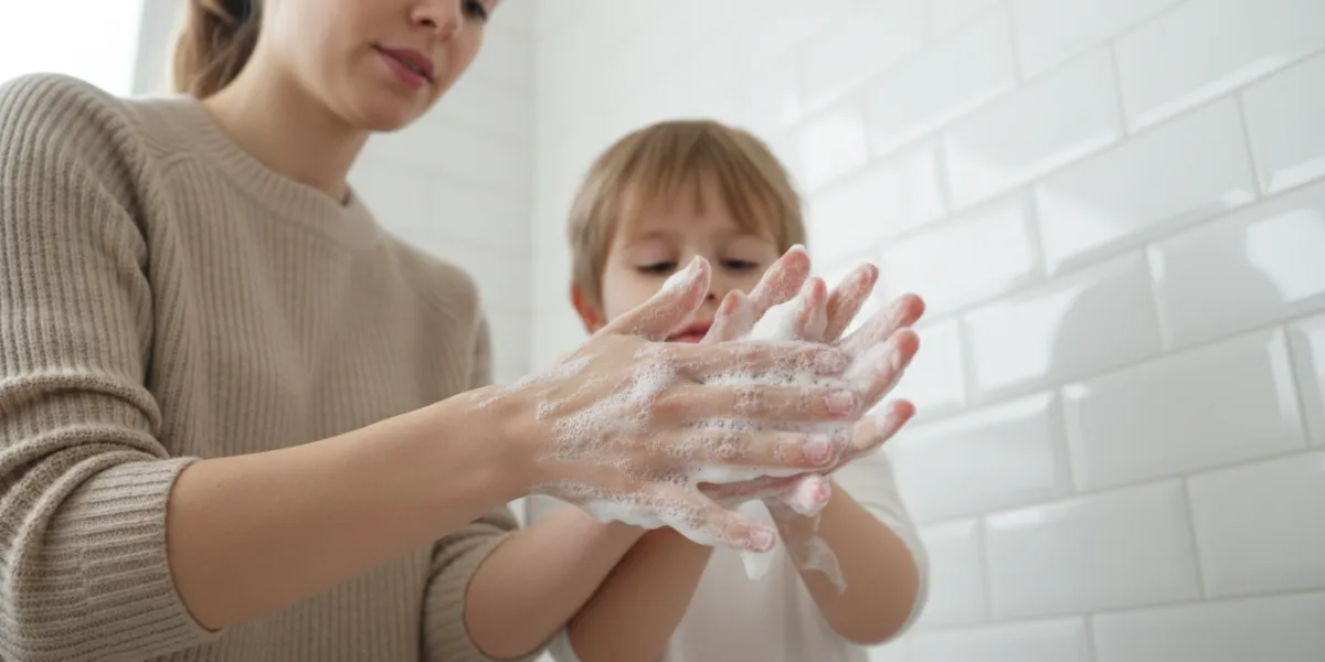 Plan moyen rapproché d'une jeune mère aux cheveux attachés, portant un pull en maille beige naturel,