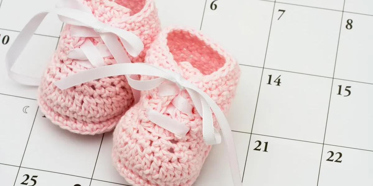 chaussons bébé rose sur un fond de calendrier, date d'échéance de bébé