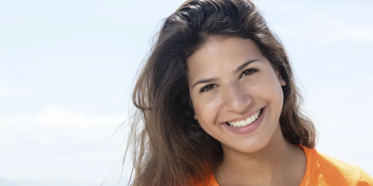heureuse femme caucasienne dans une chemise orange avec l'océan et le ciel bleu en arrière-plan heureuse femme caucasienne dans une chemise orange avec l'océan et le ciel bleu en arrière-plan