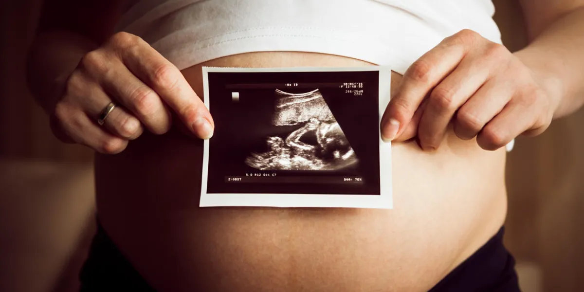 a shot of pregnant woman holding ultrasound scan