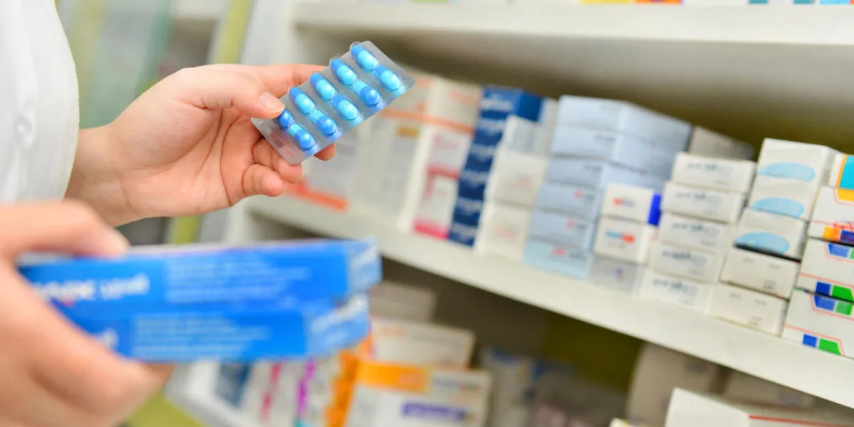 pharmacist holding medicine box and capsule pack in pharmacy drugstore