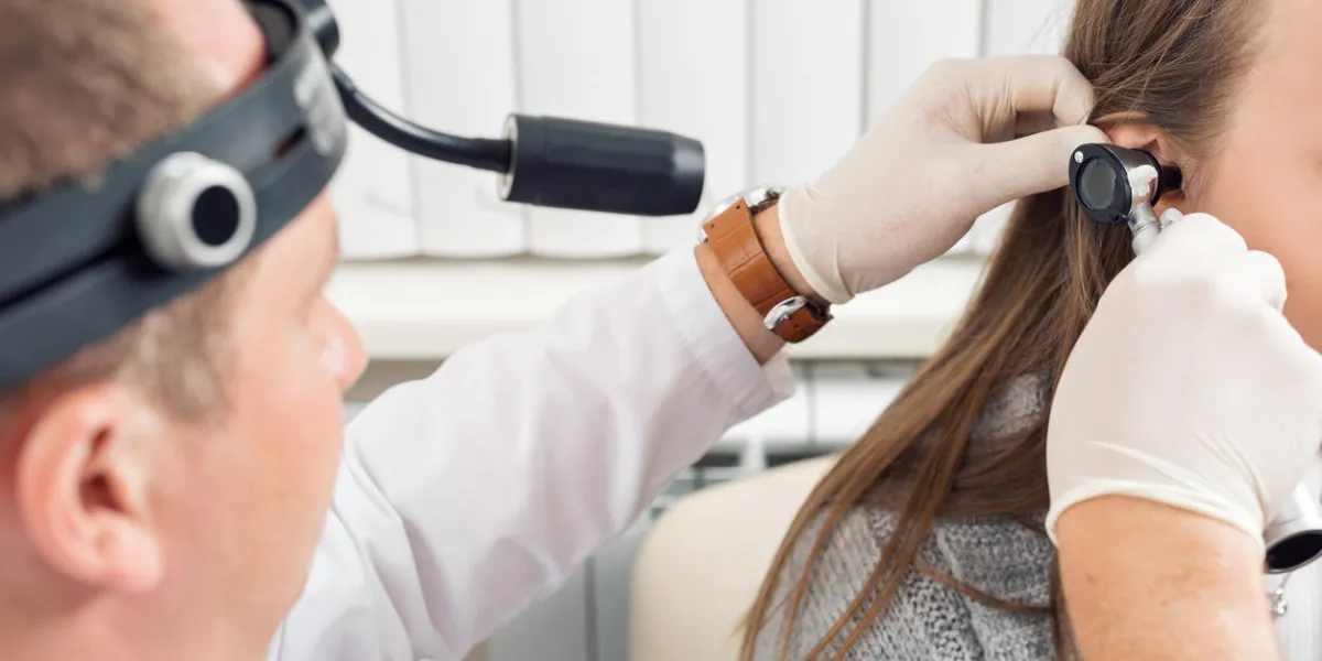 ent physician looking into patient's ear with an instrument doctor young man the patient is a young woman ent physician looking into patient's ear with an instrument doctor young man the patient is a young woman