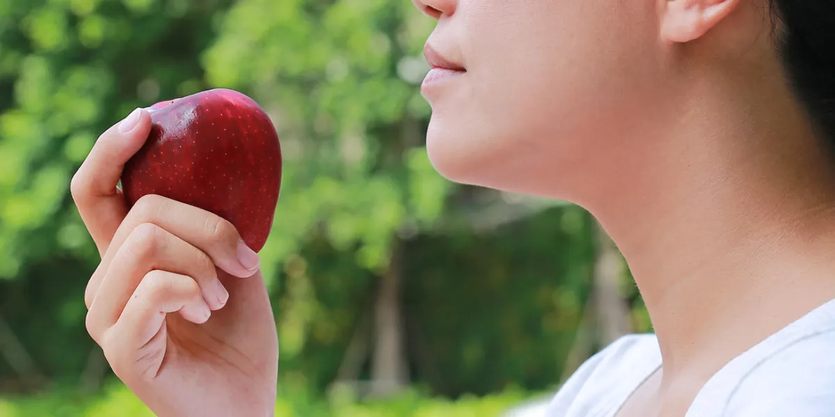 side view of young asian girl eats an apple side view of young asian girl eats an apple