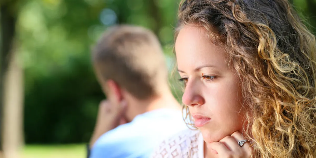 triste jeune couple assis sur le banc au parc triste jeune couple assis sur le banc au parc
