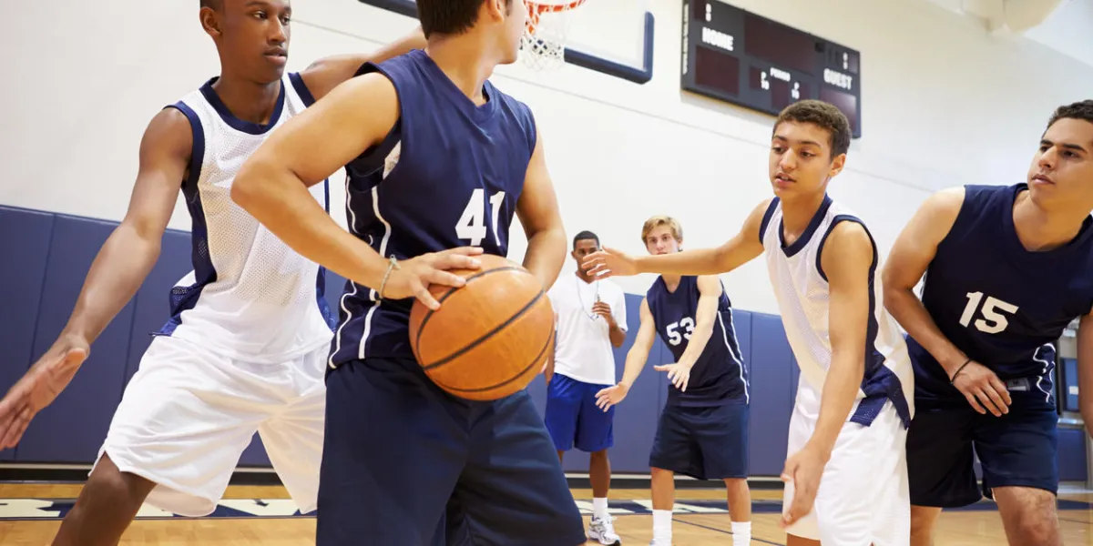 male high school basketball team playing game in gymnasium
