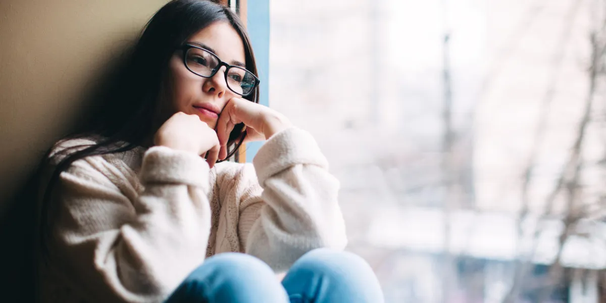 adolescente triste regardant par la fenêtre sur une froide journée d'automne