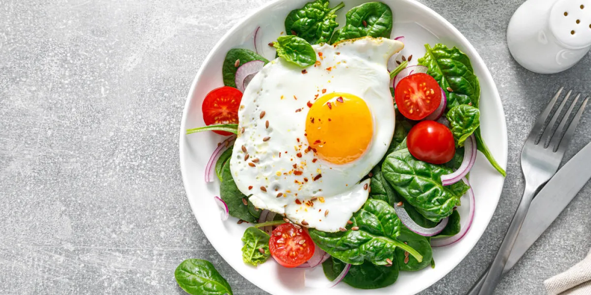 fried egg with fresh spinach tomato salad for healthy breakfast, top view fried egg with fresh spinach tomato salad for healthy breakfast, top view