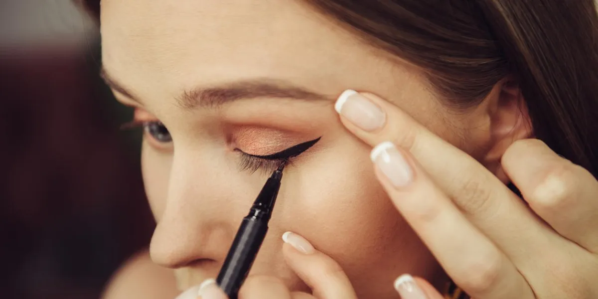 woman doing makeup and painting black arrows