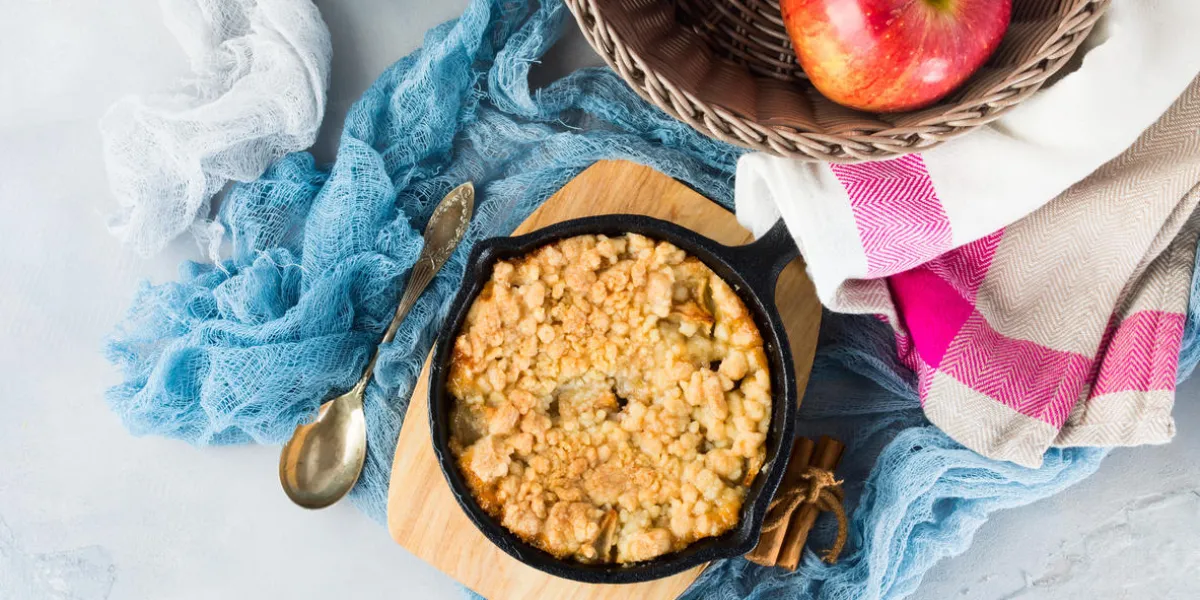 crumble aux pommes fait maison dans une poêle en fonte sur un plateau de service en bois breakfast petit déjeuner confortable et sain avec des fruits vue de dessus