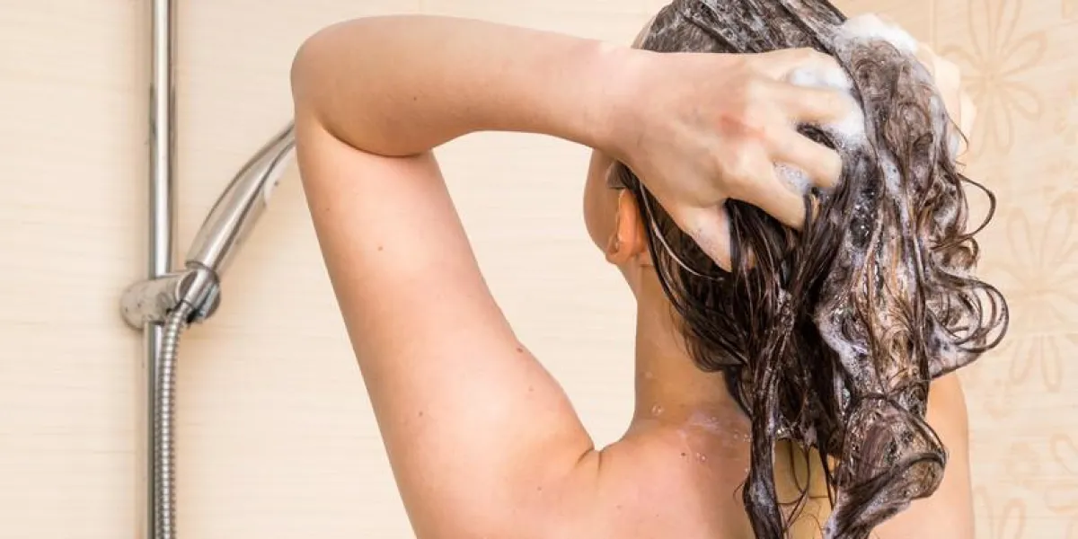 jolie femme lavant ses cheveux avec du shampoing dans la douche à la maison
