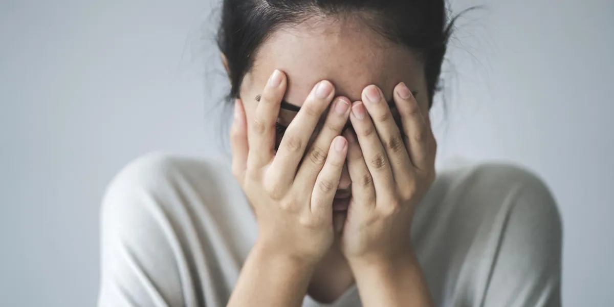 young girl covering her face with her hands
