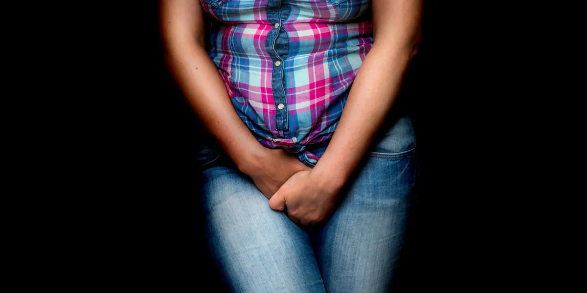 woman with hands holding her crotch, she wants to pee - urinary incontinence concept