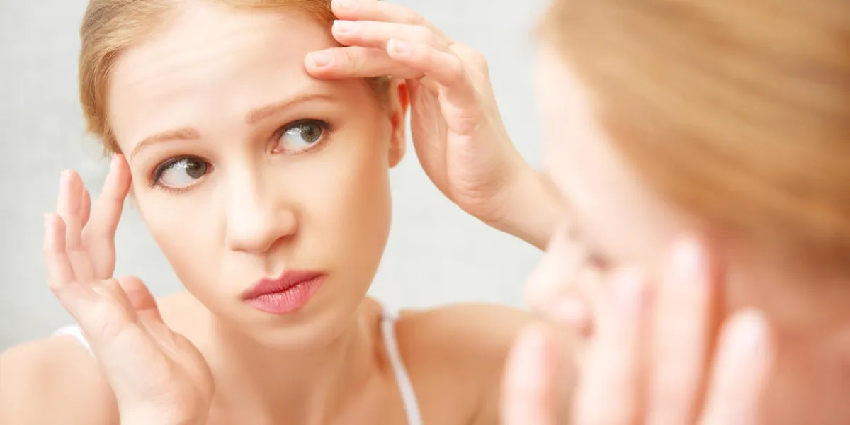 young beautiful healthy woman frightened saw in the mirror acne and wrinkles