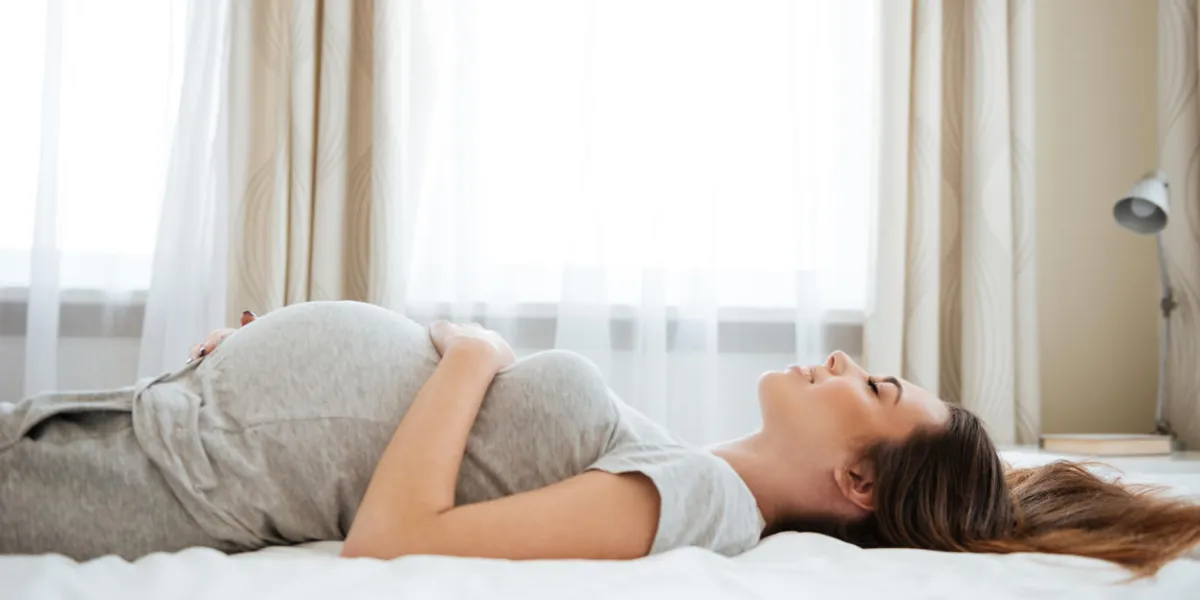 smiling pregnant young woman lying and relaxing on bed smiling pregnant young woman lying and relaxing on bed