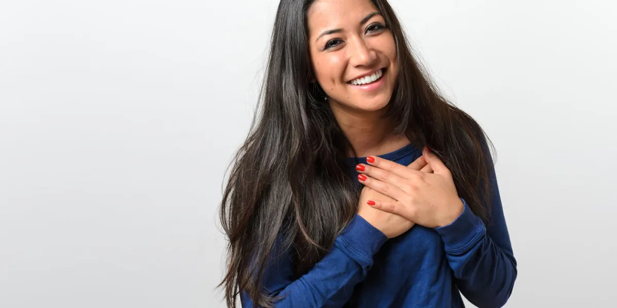 jeune femme montrant sa gratitude sincère et merci joignant ses mains à son coeur avec un sourire heureux jeune femme montrant sa gratitude sincère et merci joignant ses mains à son coeur avec un sourire heureux