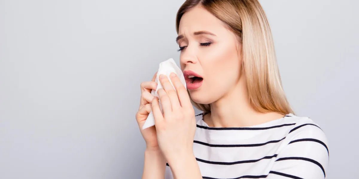 portrait with copy space, empty place of charming, unhappy, pretty woman feeling bad holding napkin in hands near face, sneezing with open mouth, isolated on grey background portrait with copy space, empty place of charming, unhappy, pretty woman feeling bad holding napkin in hands near face, sneezing with open mouth, isolated on grey background