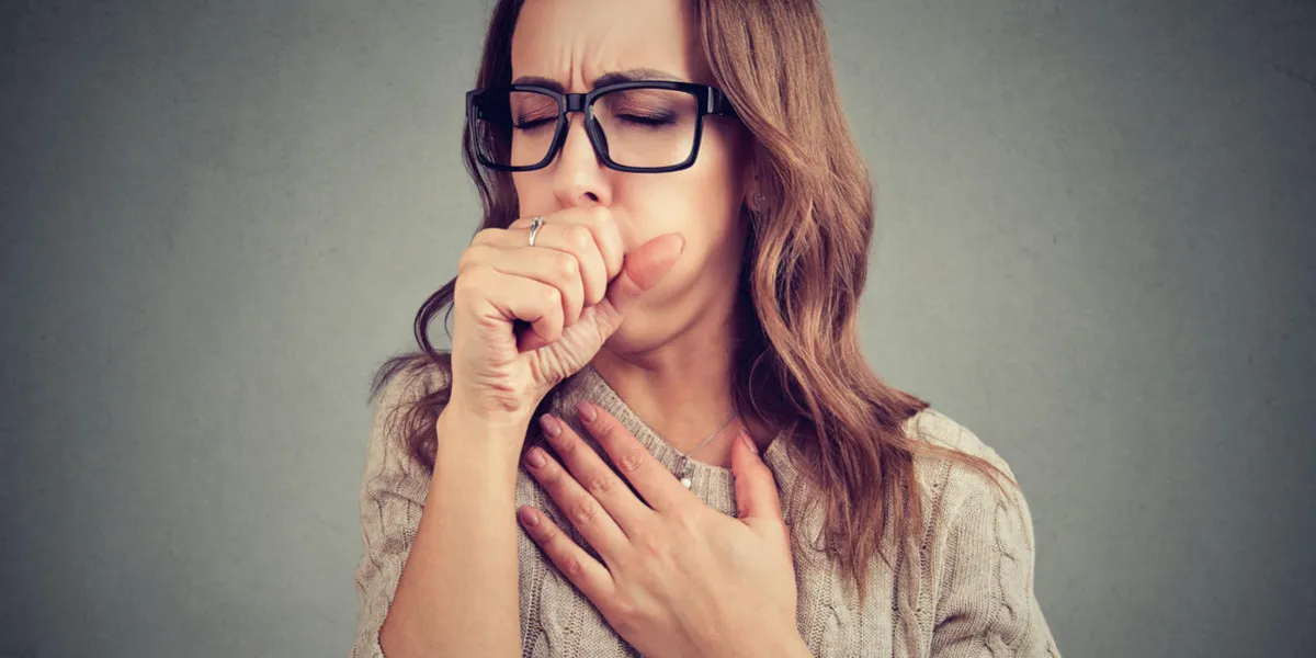 young woman having asthma problems and coughing badly covering mouth and holding hand on chest