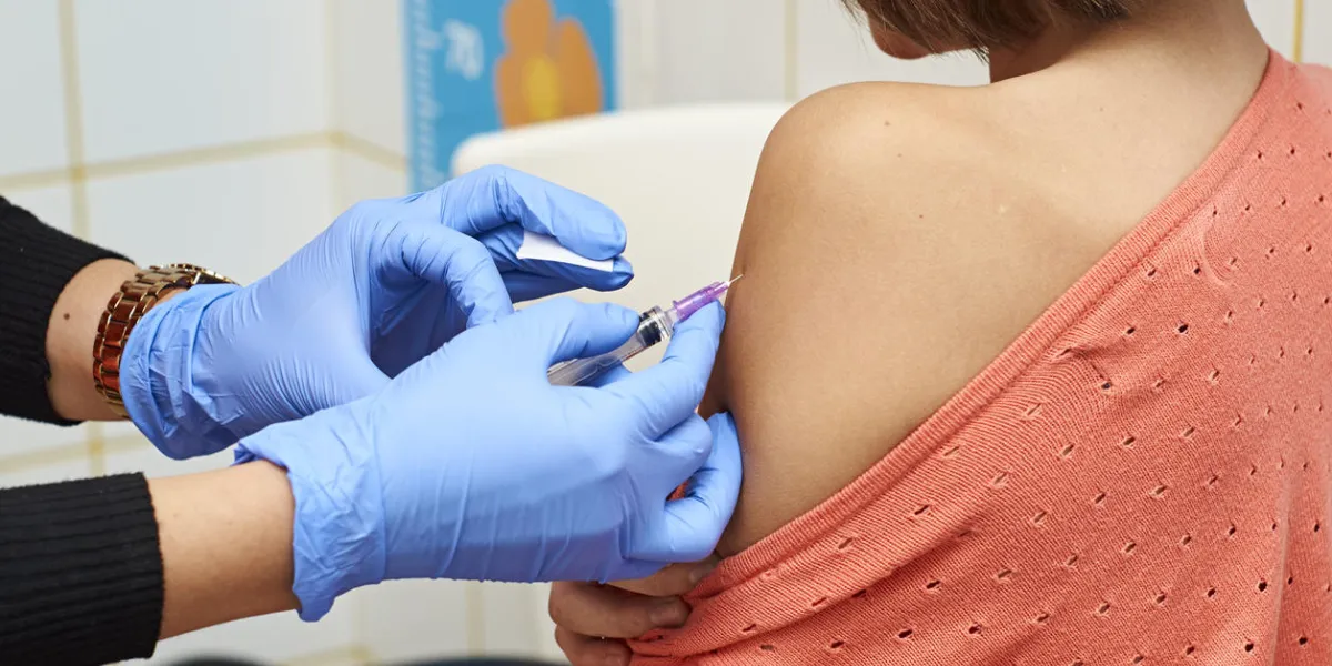 infirmière faisant injection de vaccin à l'épaule de l'adolescente