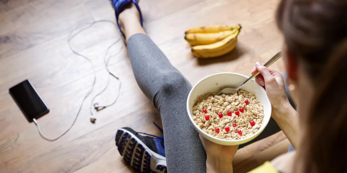 young girl eating a oatmeal with berries after a workout fitness and healthy lifestyle concept